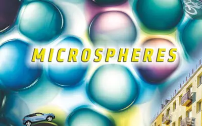 Graphic of a headline reading "Microspheres" on a background of colorful microscopic bubbles that resemble water droplets. A tiny SUV drives over the top of one of these bubbles, and a picture of the side of a building is used decoratively in the corner of the graphic.