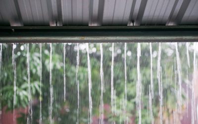 Streams of rain water pour off a corrugated roof