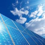 Group of solar panels on a blue sky with clouds and sun rays - Concept of solar energy