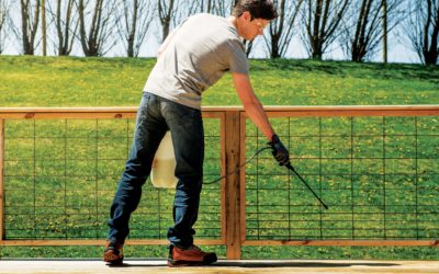 man spraying wood deck with preservative