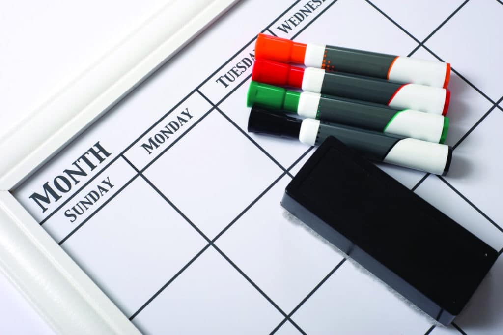 Blank white calendar with dry erase markers and an eraser