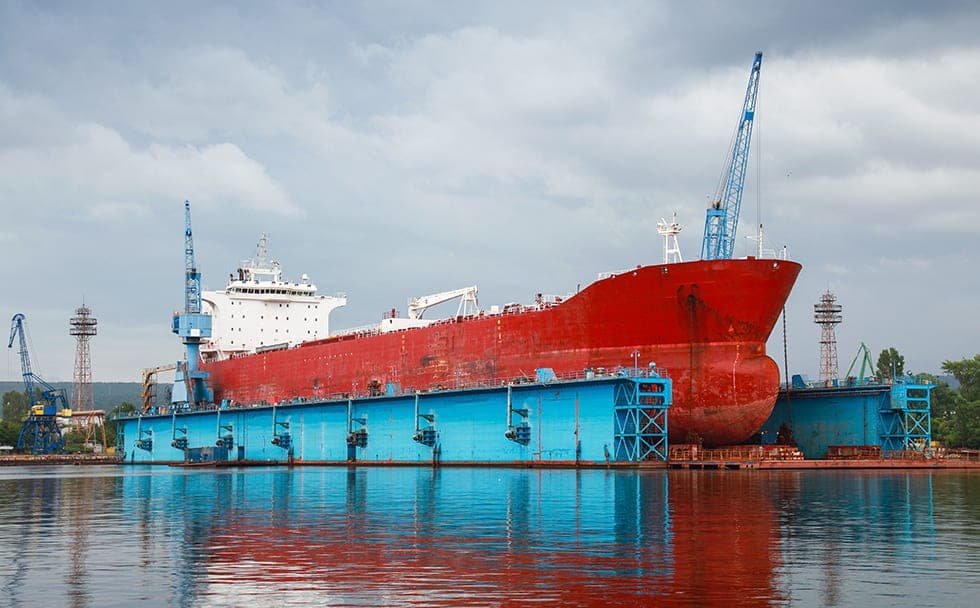 Big red tanker under repairing in blue floating dock