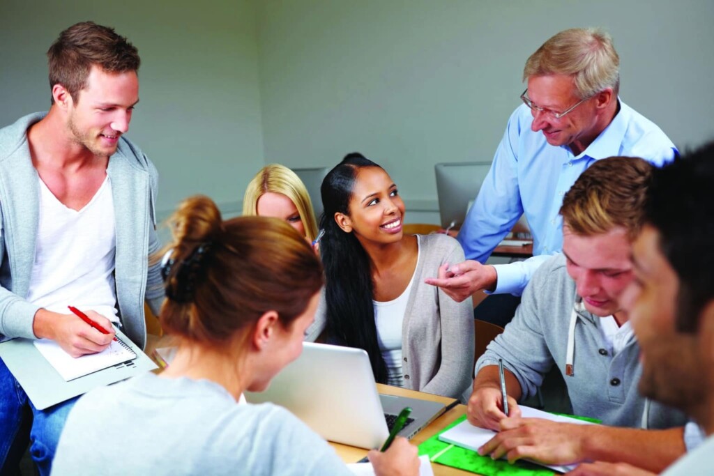 Teacher helping college students in study class