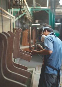 Factory worker spray painting furniture parts at an assembly line