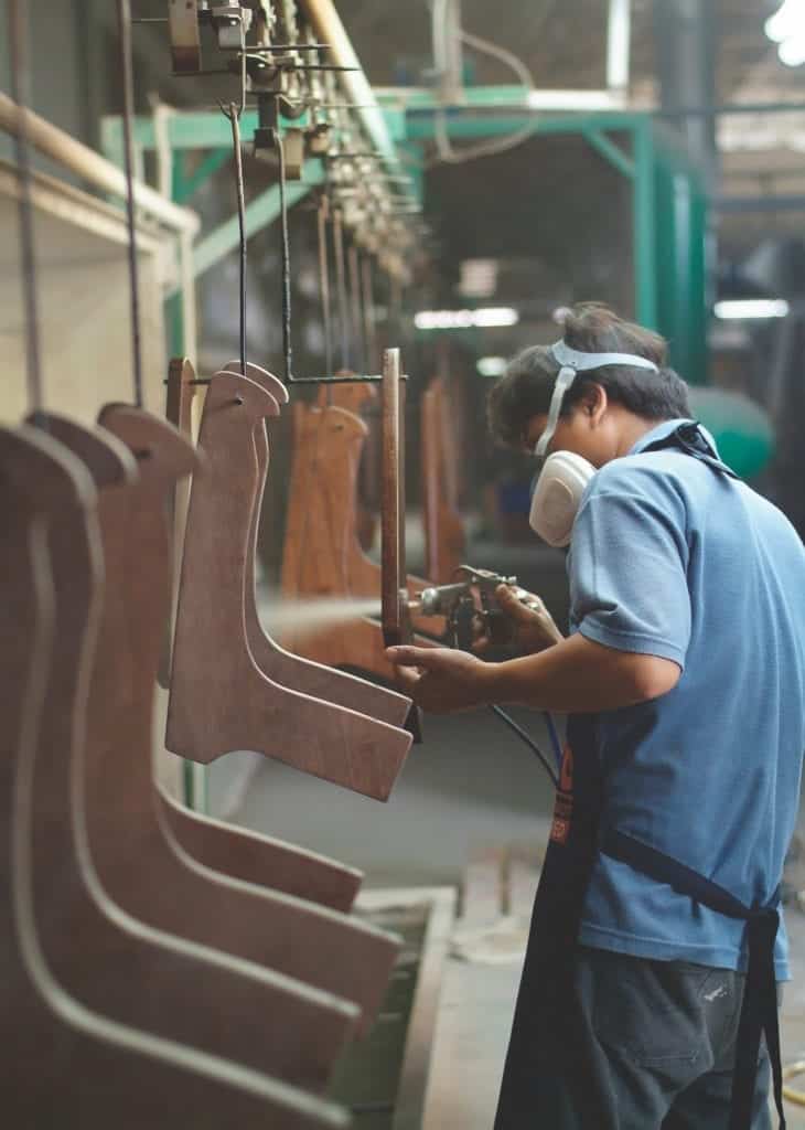 Factory worker spray painting furniture parts at an assembly line