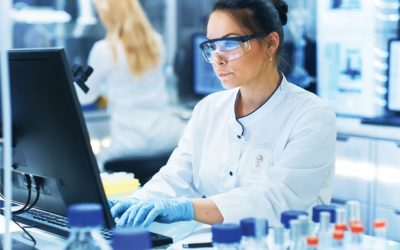 Medical Research Scientist Typing Information Obtained from New Experimental Drug Trial. She Works in a Bright and Modern Laboratory.