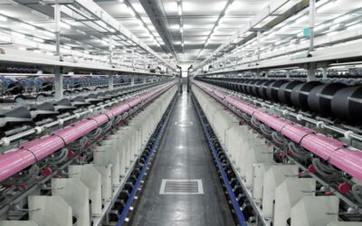 Manufacturing plant aisle shown with fluorescent lights and a concrete floor.