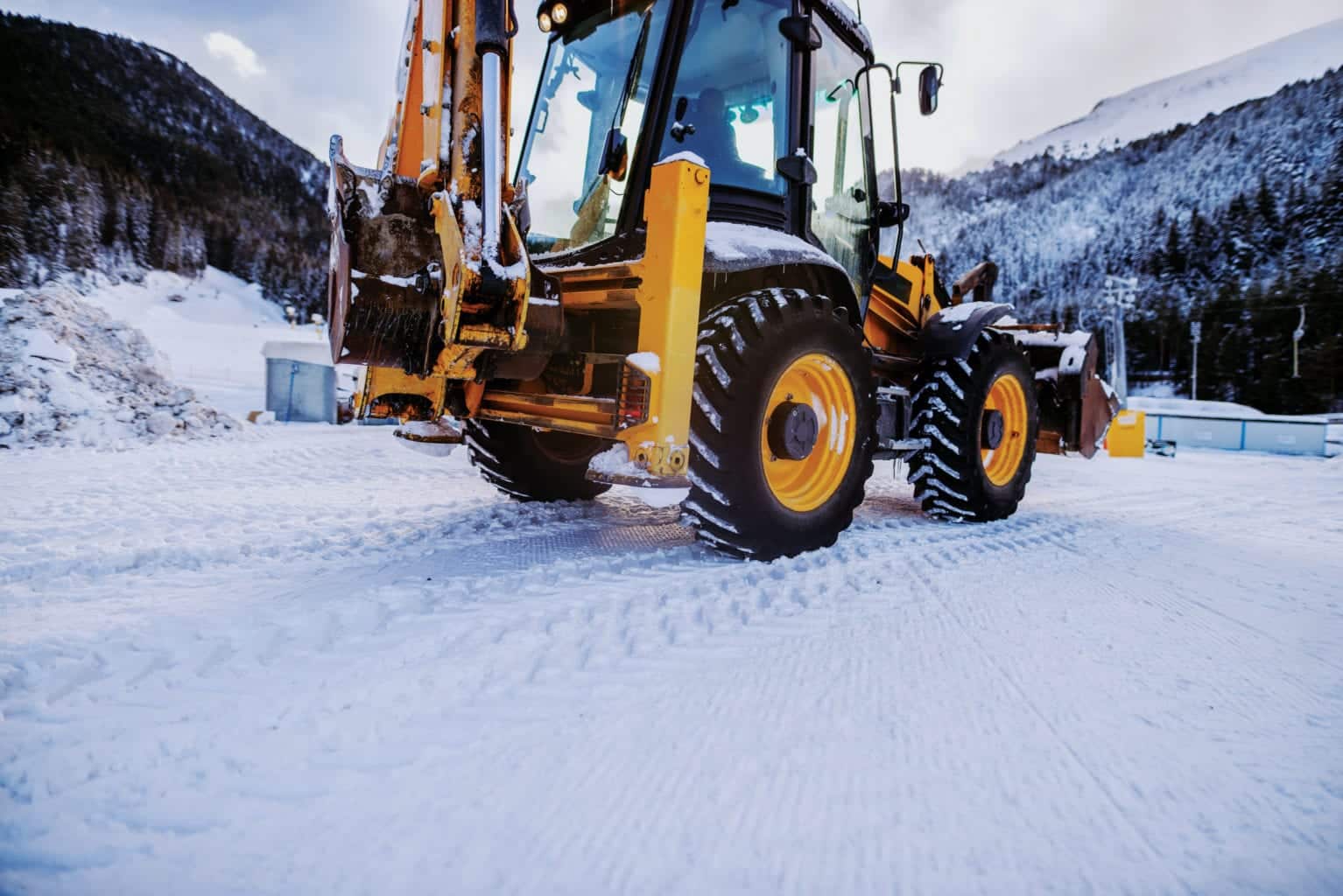 Bulldozer cleaning snow on mountain. Making road clean for car.