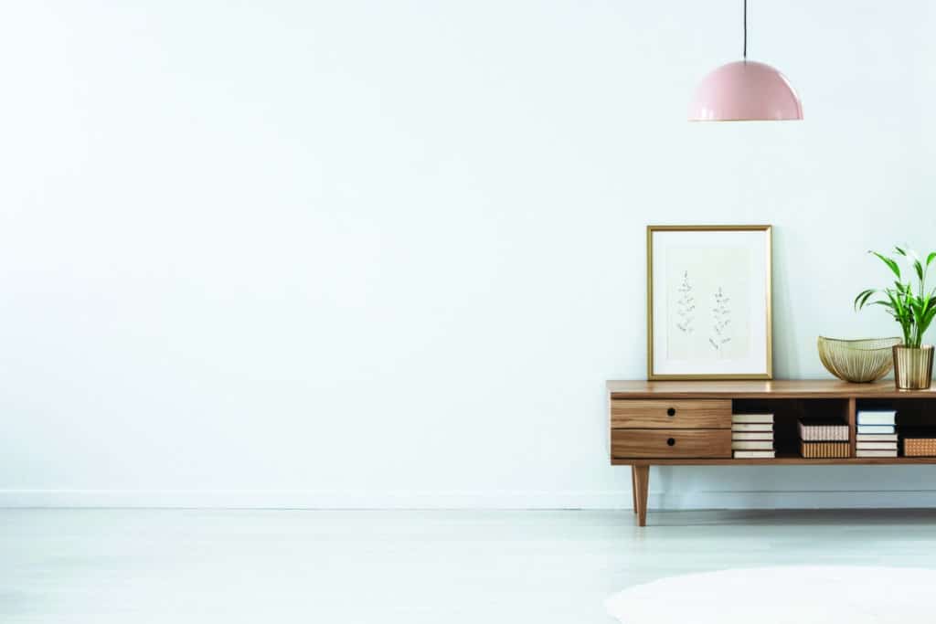 Retro pink ceiling lamp above a wooden sideboard in a modern living room interior