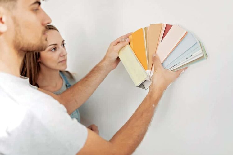 Young couple choosing the right color for their wall while renovating apartment. DIY concept