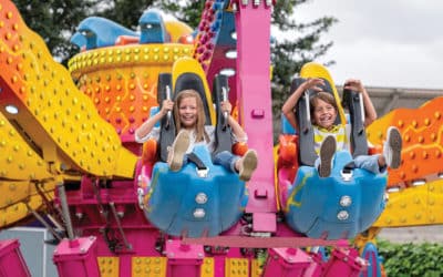 Happy kids having fun in an amusement park riding on a fun ride and screaming - lifestyle concepts