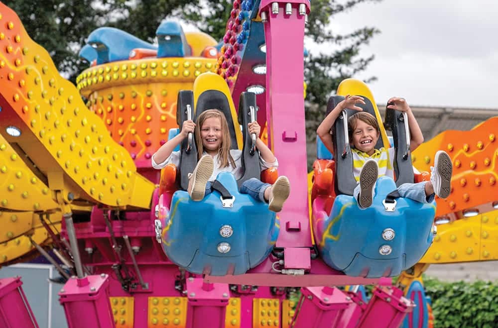 Happy kids having fun in an amusement park riding on a fun ride and screaming - lifestyle concepts