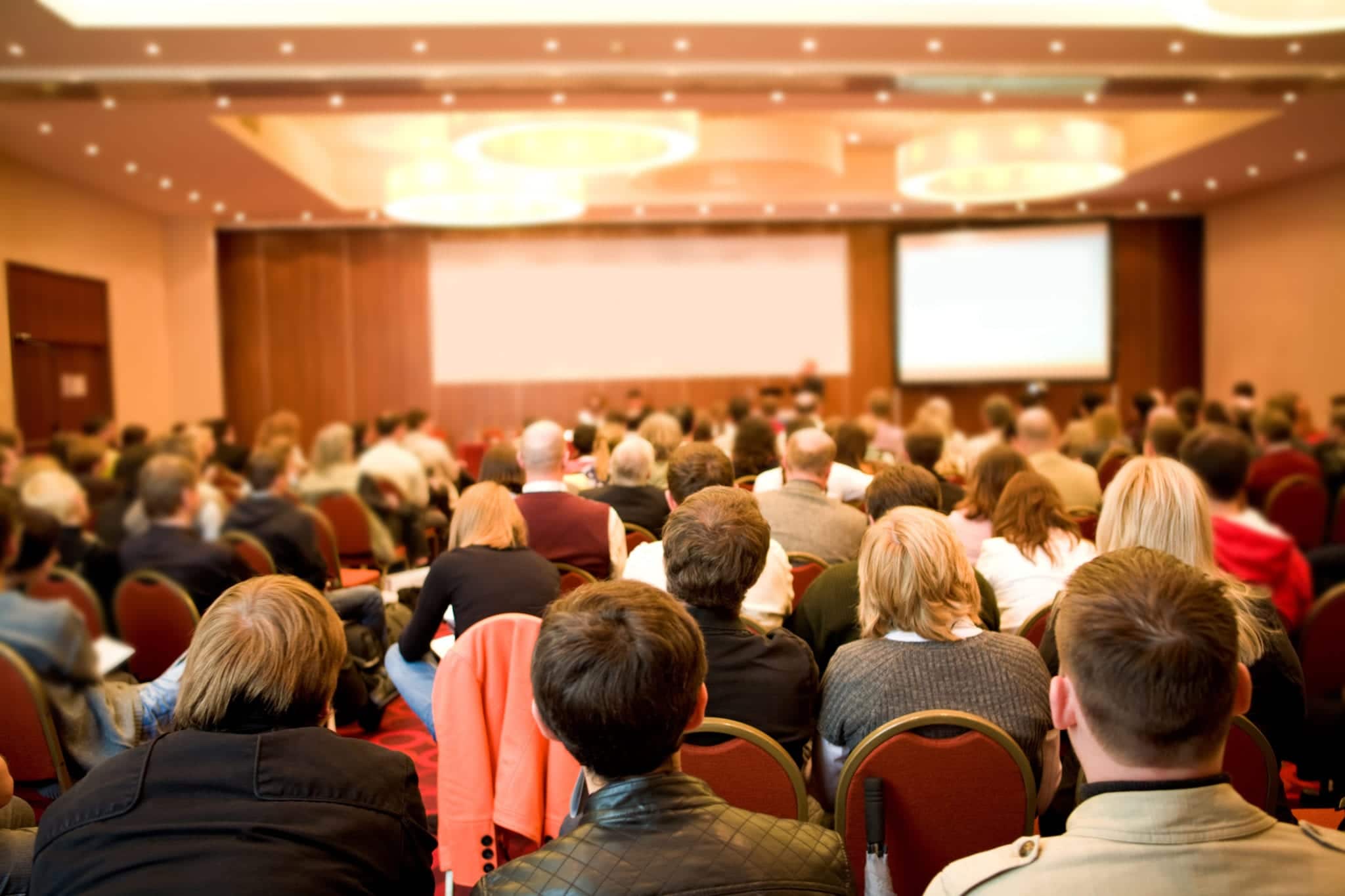 Rear view of many listeners sitting on chairs during lecture at conference