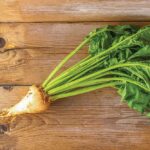 Sugar beet with tops on an old wooden table.