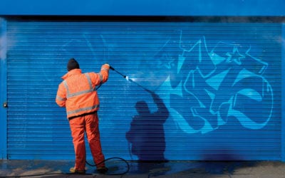 Washing graffiti off a security grill.