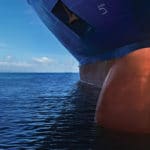 Close up of large blue merchant crago ship in the middle of the ocean underway. Performing cargo export and import operations.