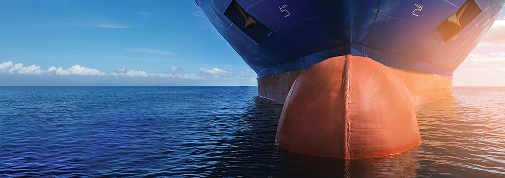 Close up of large blue merchant crago ship in the middle of the ocean underway. Performing cargo export and import operations.