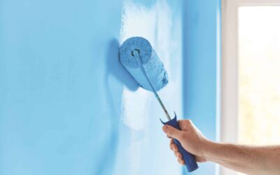 Male hand painting wall with paint roller. Painting apartment, renovating with blue color paint