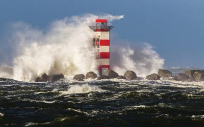 Big waves crashing against the lighthouse at the tip of the pier of Ijmuiden, Netherlands, during severe storm over the North Sea.