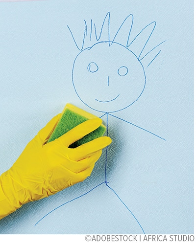 rubber glove wiping away a child's drawing on wall