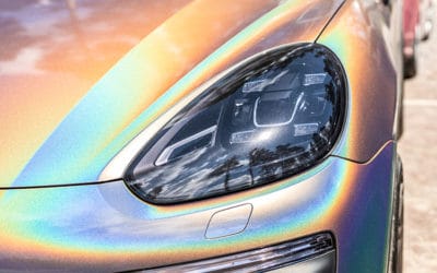 Close-up LED headlight expensive car part with exclusive iridescent painting. Vehicle covered with vibrant chameleon film