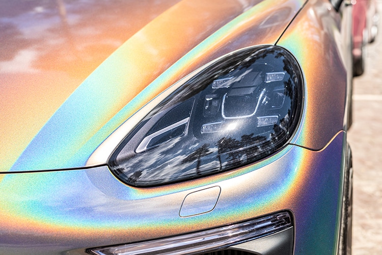 Close-up LED headlight expensive car part with exclusive iridescent painting. Vehicle covered with vibrant chameleon film