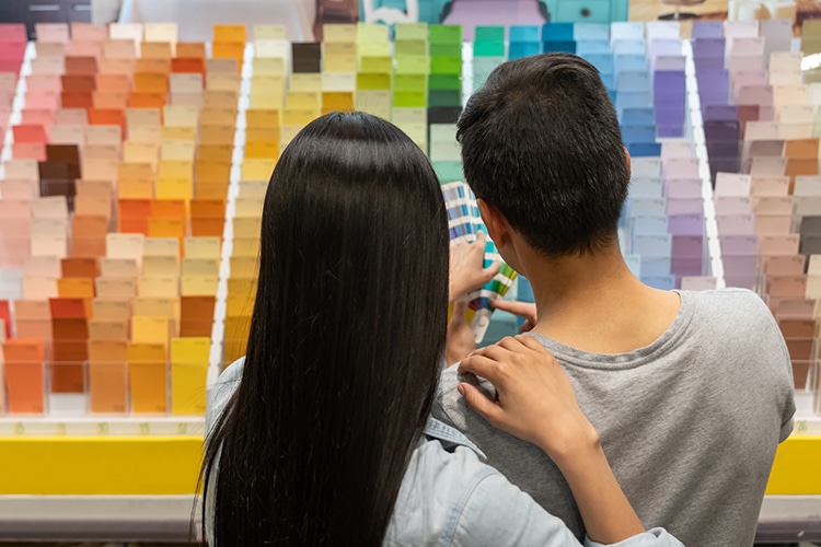 Couple at hardware store choosing a color for their house project