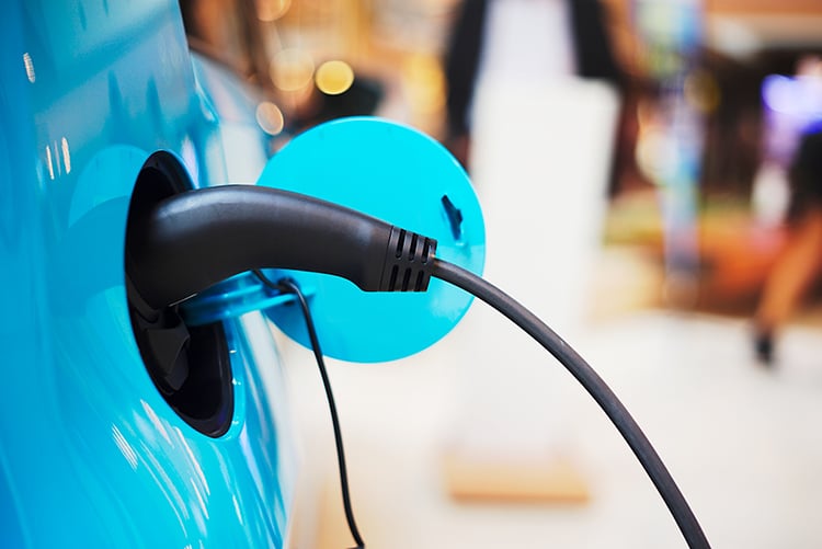 Close up view of a charging station connector plugged into an electric car.