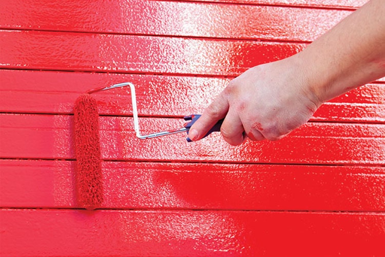 hand rolling red paint on wall