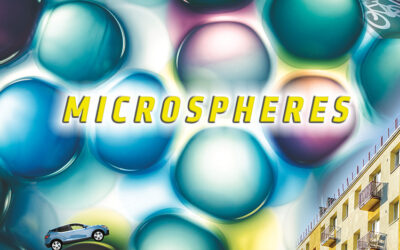 Graphic of a headline reading "Microspheres" on a background of colorful microscopic bubbles that resemble water droplets. A tiny SUV drives over the top of one of these bubbles, and a picture of the side of a building is used decoratively in the corner of the graphic.