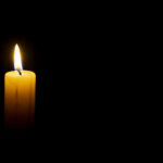 A single pillar candle burns in the dark.