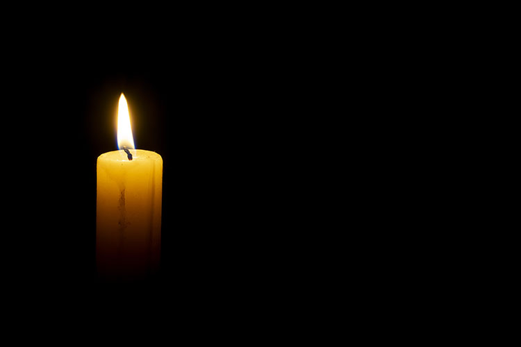 A single pillar candle burns in the dark.