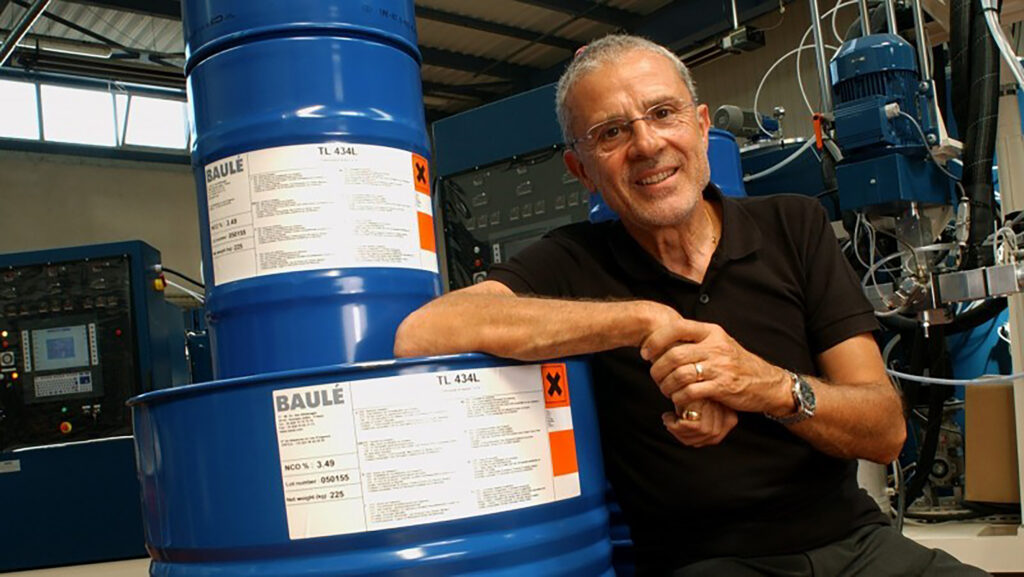 Michel Baulé, Covestro Elastomer founder, next to a blue barrel bearing his last name.