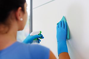 Woman holding a detergent and cleaning walls at home